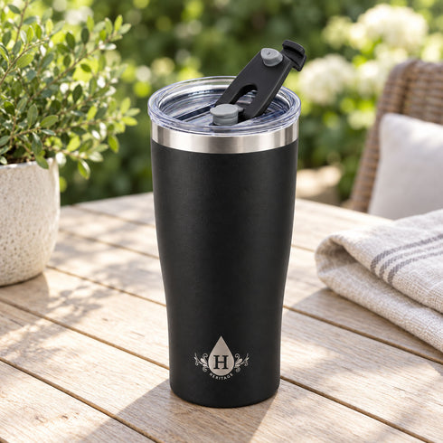 Matte black Heritage tumbler with flip-back spout lid open on a patio table