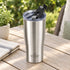Brushed stainless steel Heritage tumbler with flip-back spout lid open on a patio table