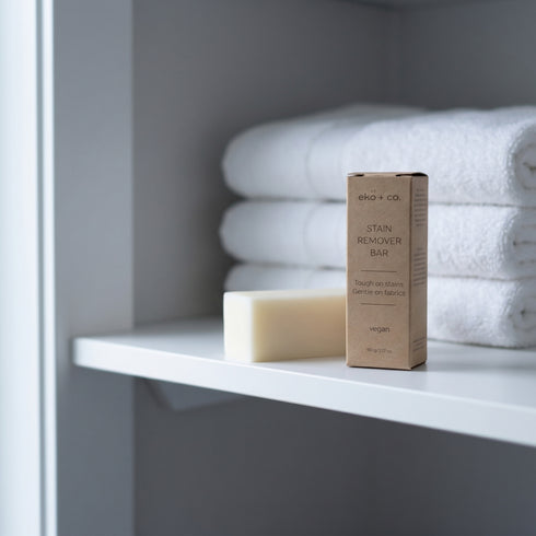 eko + co. Stain Remover Bar displayed on linen closet shelf with folded white towels — zero-waste home setting