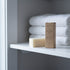 eko + co. Stain Remover Bar displayed on linen closet shelf with folded white towels — zero-waste home setting